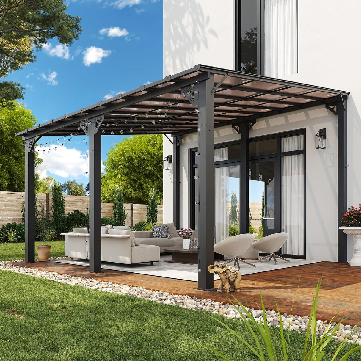 Patioslife 10×12ft patio pergola with dark frame, outdoor sofa seating, string lights, and garden setting beside a modern house